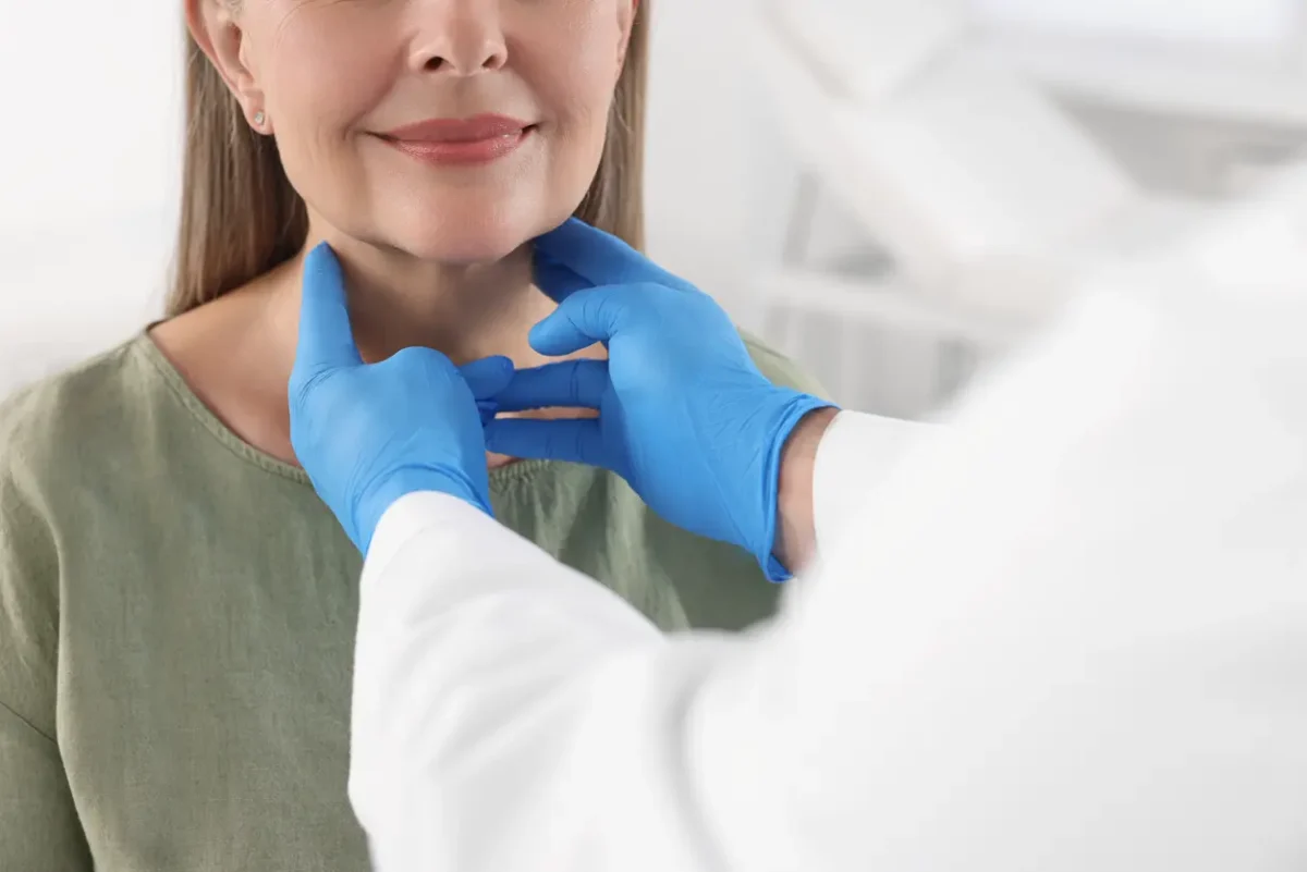 Woman undergoing a neck and jawline evaluation during a facial plastic surgery consultation, illustrating assessment of the neck area during facelift planning.